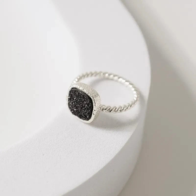 Silver ring with a black gemstone on a white surface