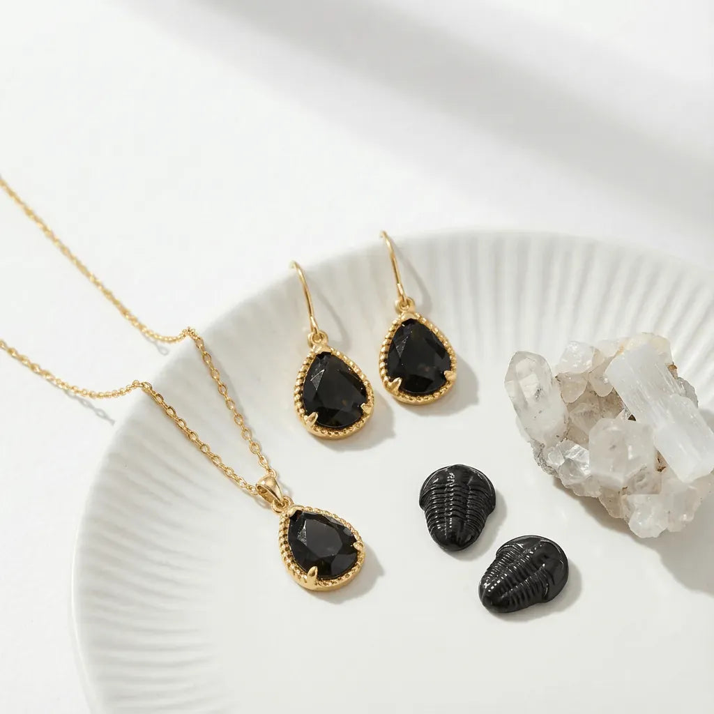 Jewelry set with black stones and gold accents on a white surface