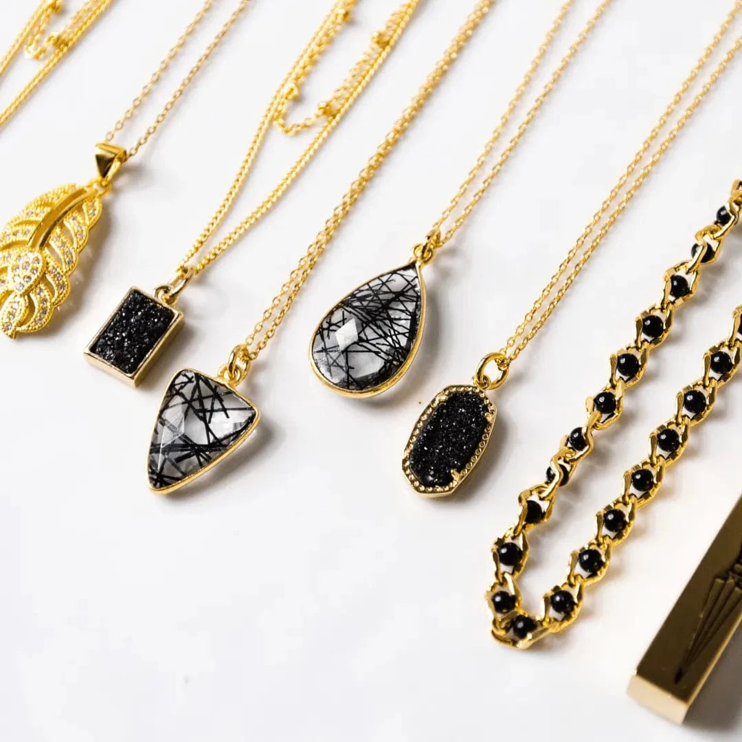 Gold necklaces with various pendants on a white background