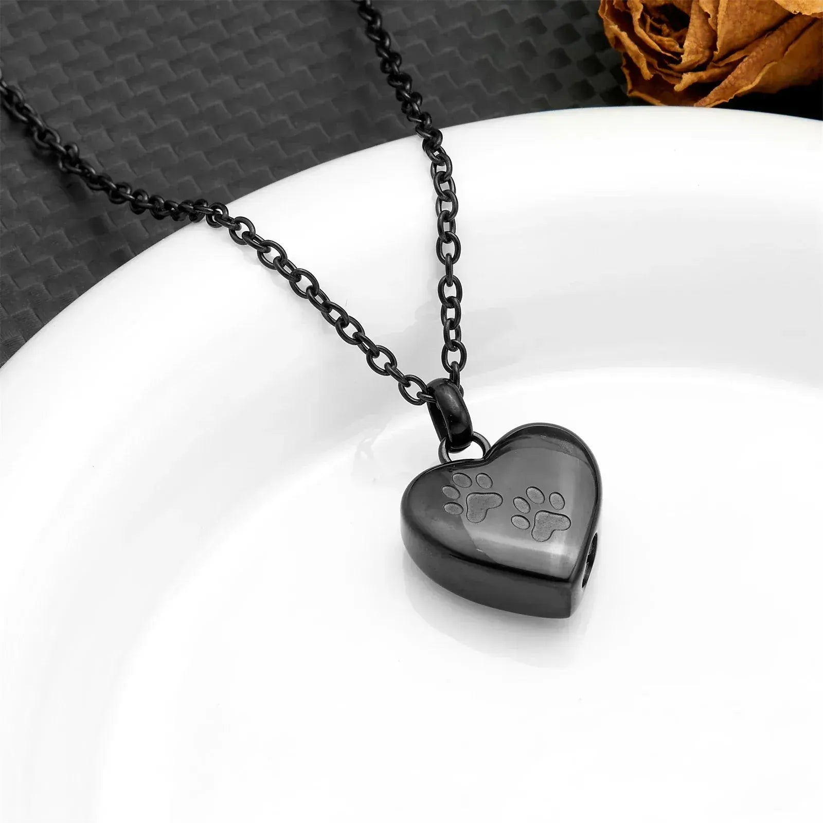 Heart-shaped pendant with paw prints on a chain against a white background