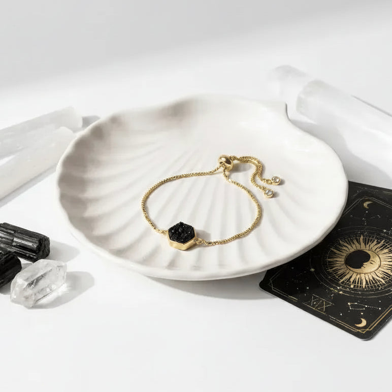 Druzy Hex Bracelet on a white dish with black agate stones, crystals, and tarot cards on a white background.