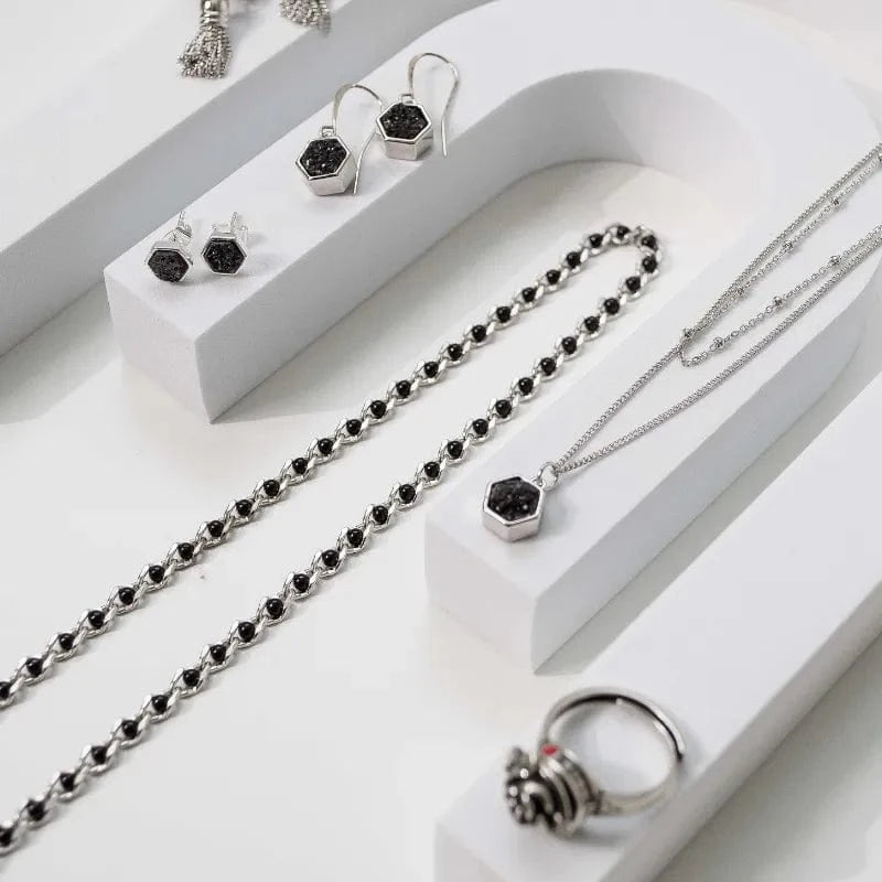 Silver jewelry set with black stones on a white surface