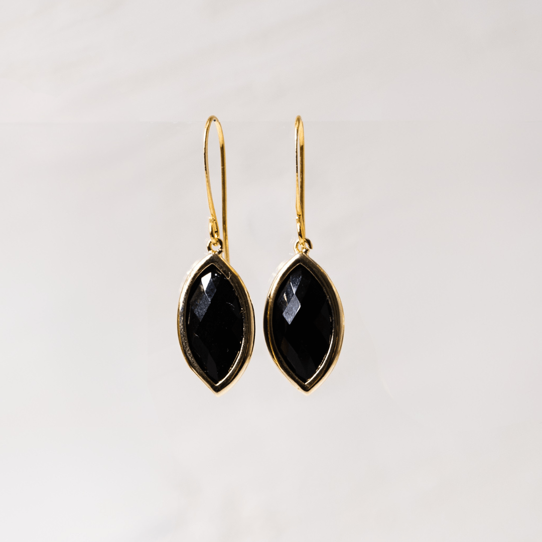 Gold earrings with black stones on a light gray background