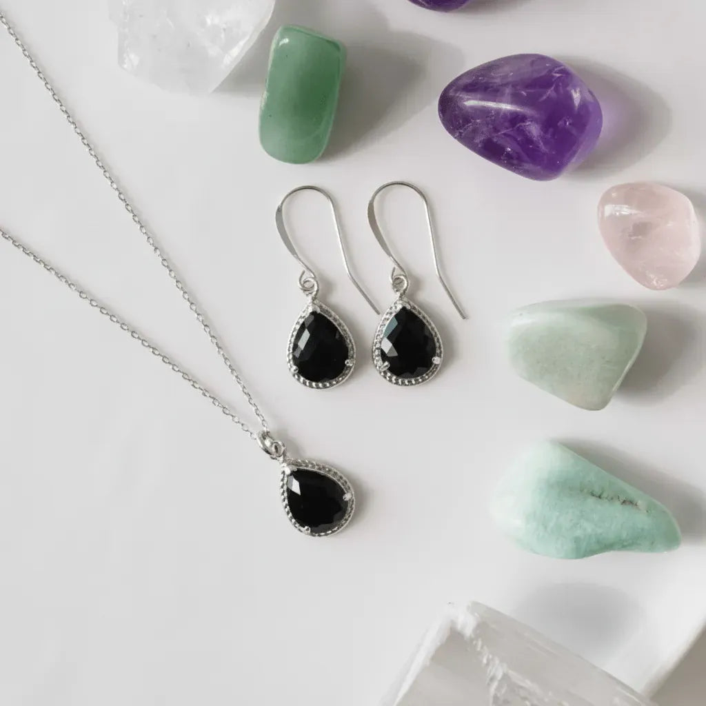 Jewelry set with pendant and earrings on a white surface with crystals.