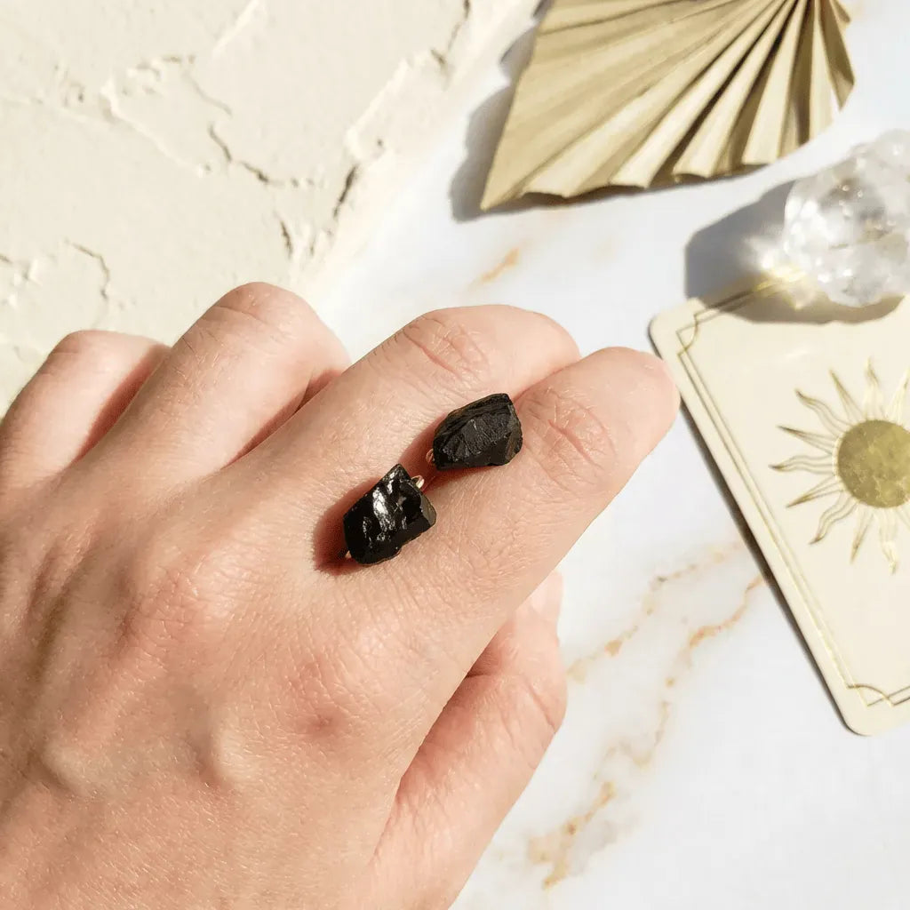 Hand holding two black stones with a marble surface and card in the background