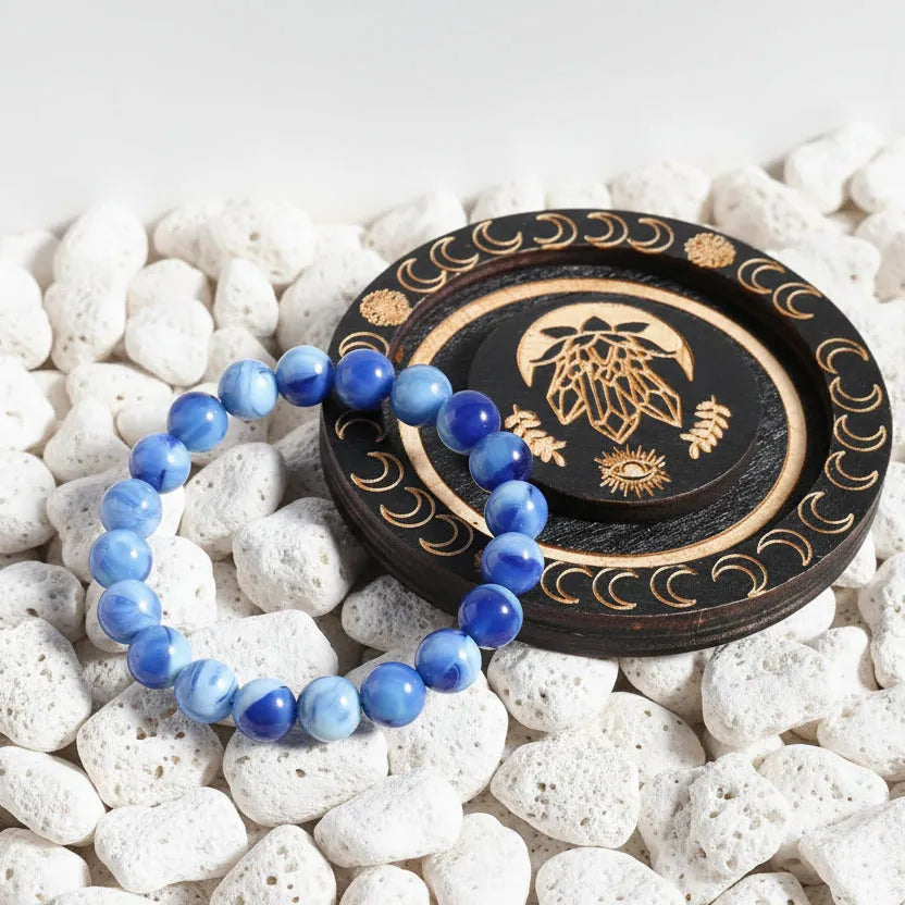 Blue beaded bracelet on a wooden surface with decorative coaster
