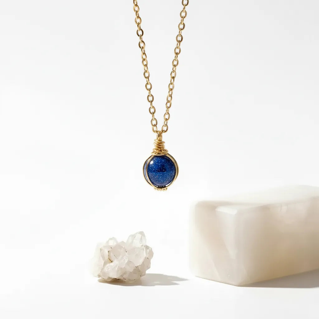 Gold necklace with a blue sandstone pendant on a white background