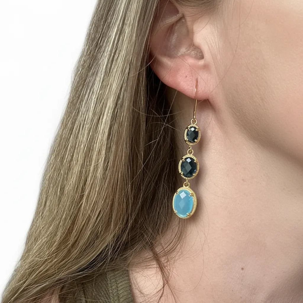 woman wearing gold blue topaz three-stone drop earrings — one-of-a-kind crystal jewelry for calm