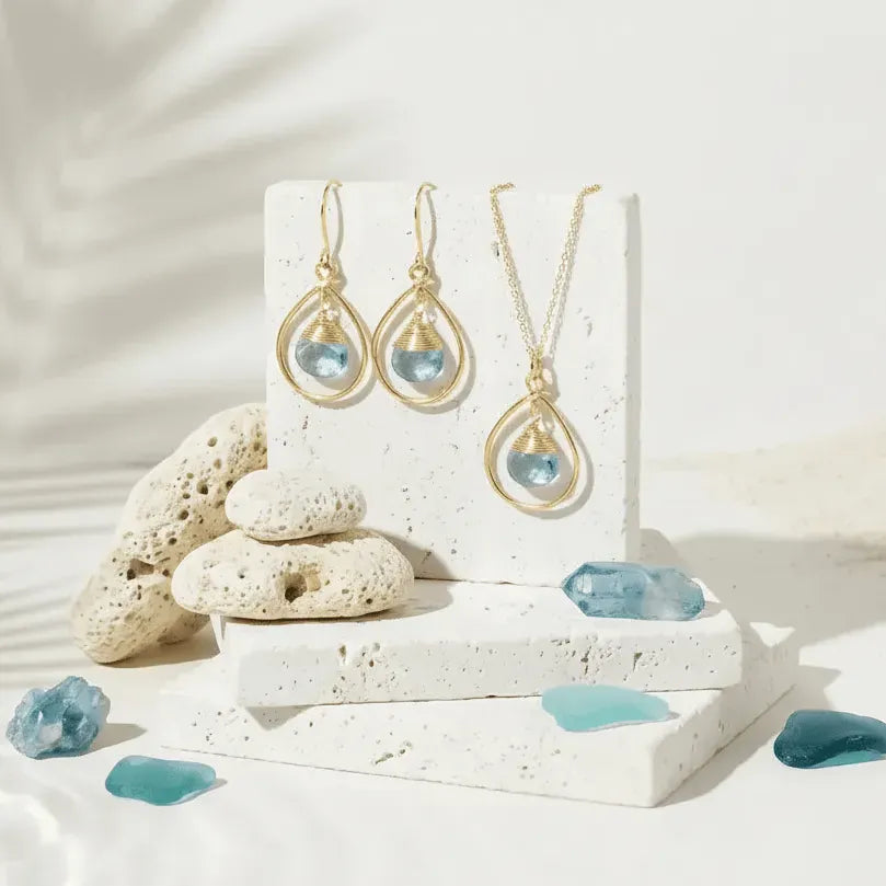 Jewelry set with gold necklaces and earrings featuring blue gemstones on a white background.