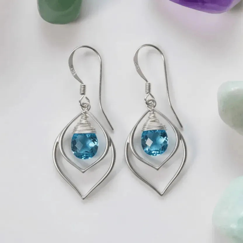 Silver earrings with blue gemstones on a light background