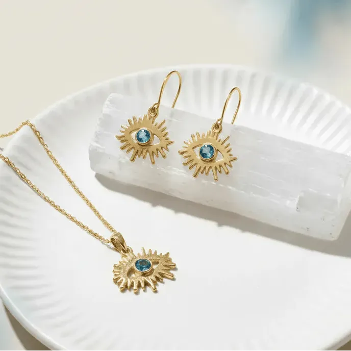 Gold necklace and earrings with blue gemstones on a white dish