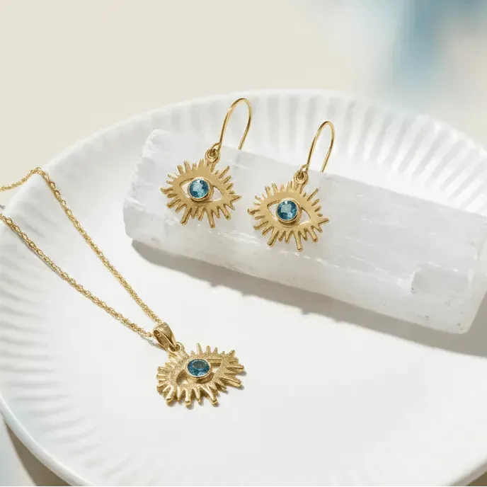 Gold necklace and earrings with blue gemstones on a white dish