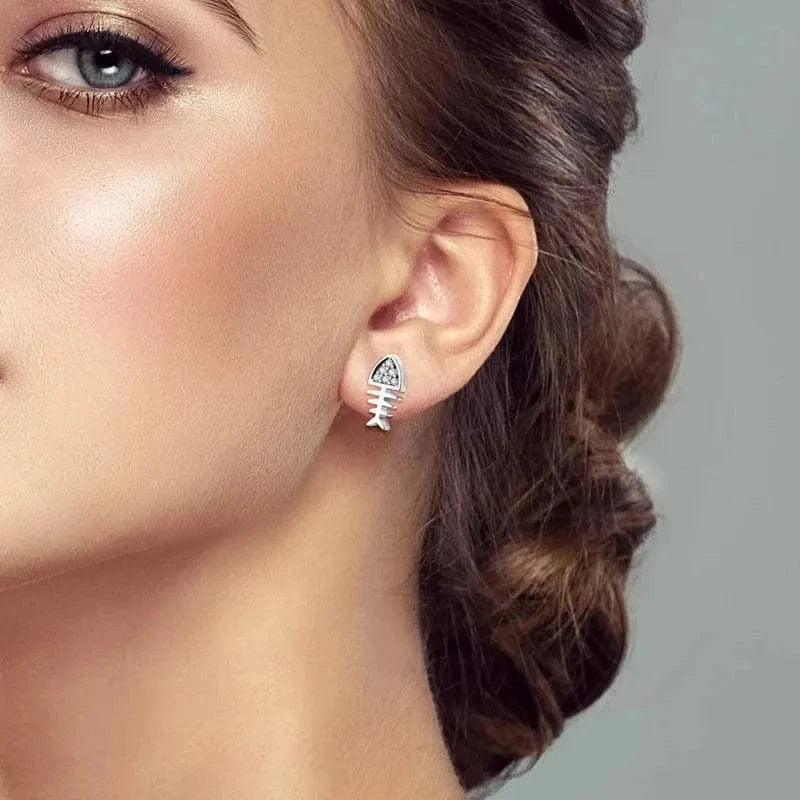 Close-up of a woman wearing fish-shaped earrings with a neutral background
