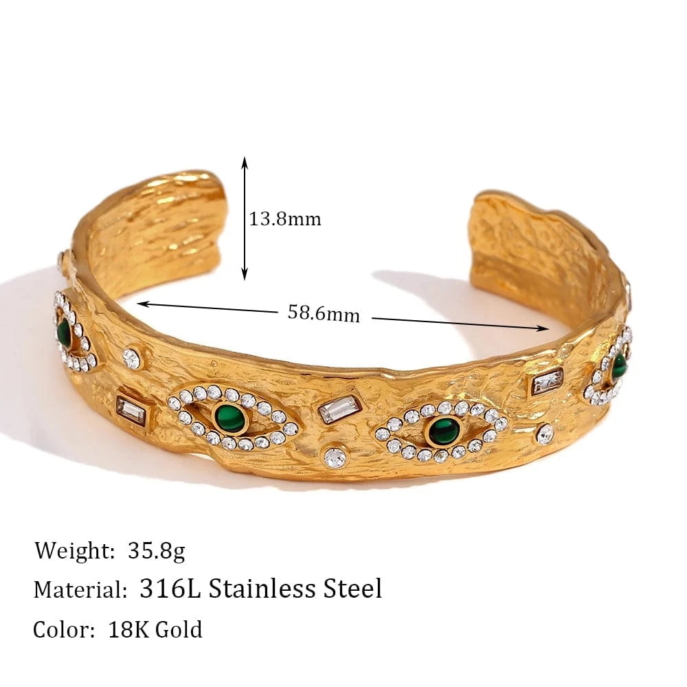 Gold bracelet with eye designs and measurements on a white background