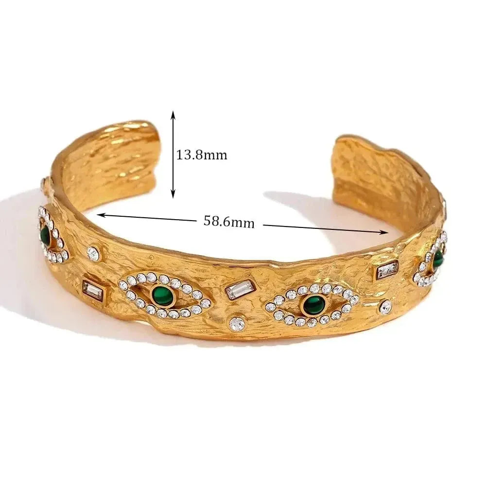 Gold bracelet with eye designs and measurements on a white background