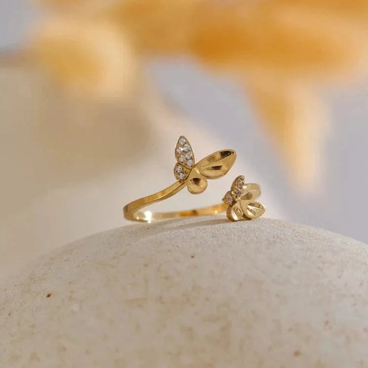 Gold butterfly ring on a stone with a blurred natural background