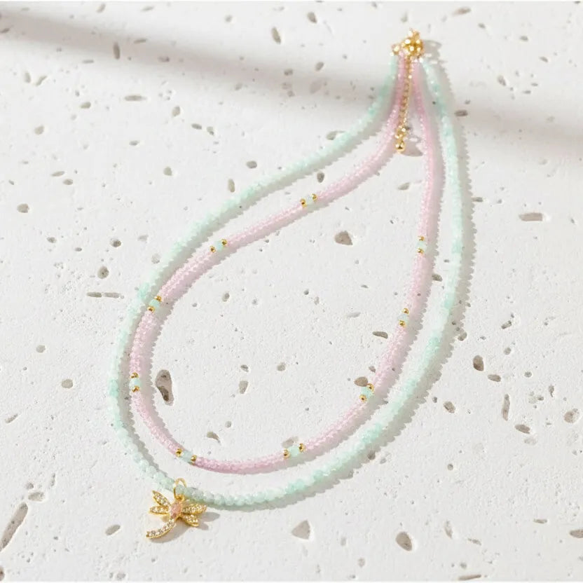 Pastel beaded necklace with a small pendant on a light gray background