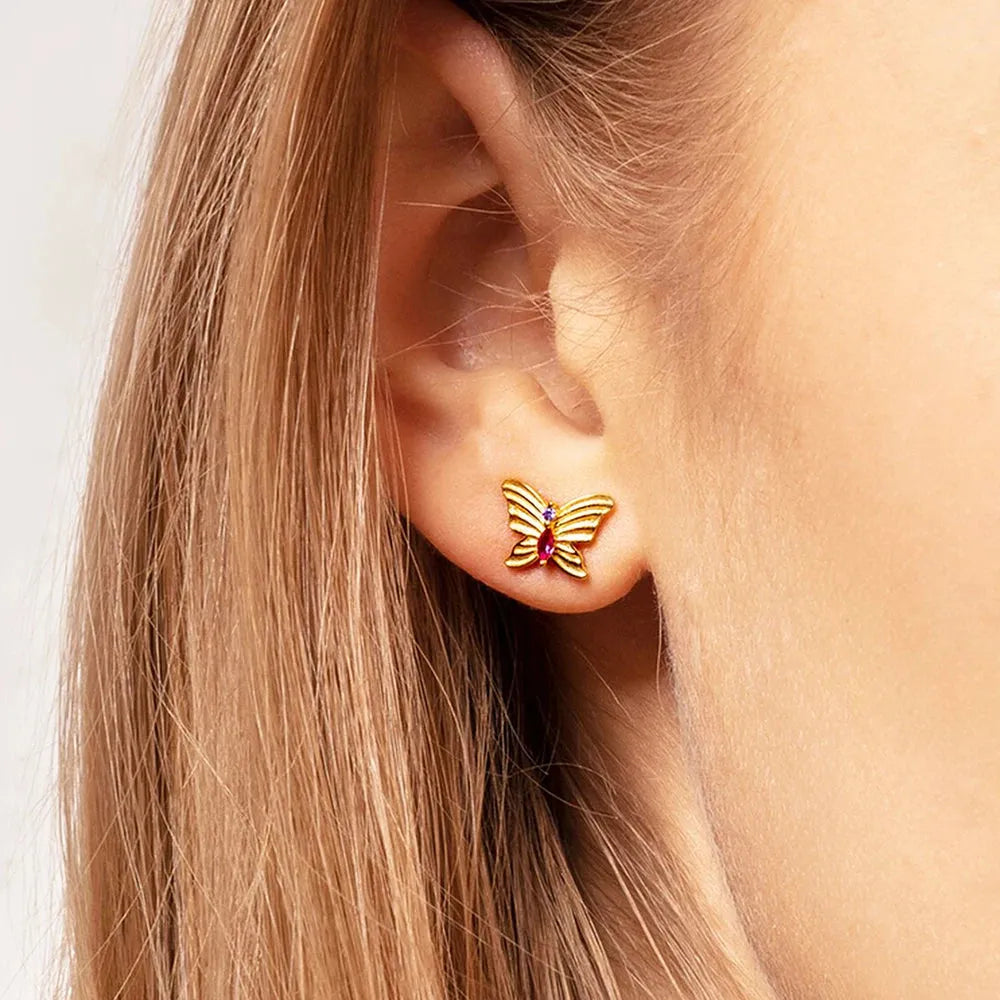 Butterfly earring worn by a person with blonde hair.