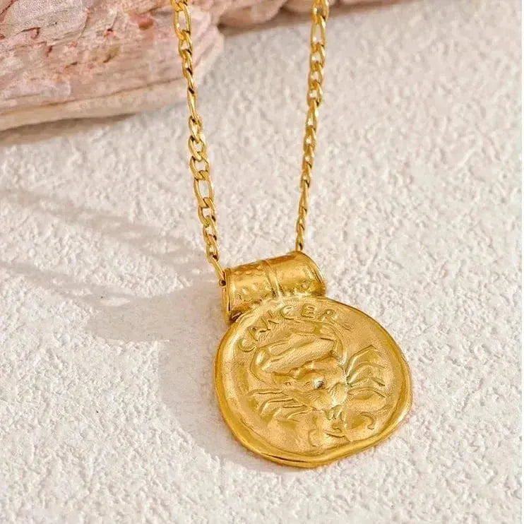 Gold necklace with a zodiac pendant on a textured surface