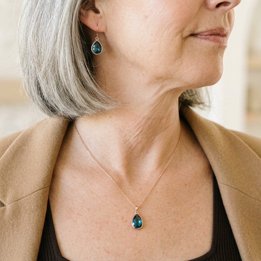Woman wearing a silver Capri blue faceted glass teardrop necklace and matching earrings