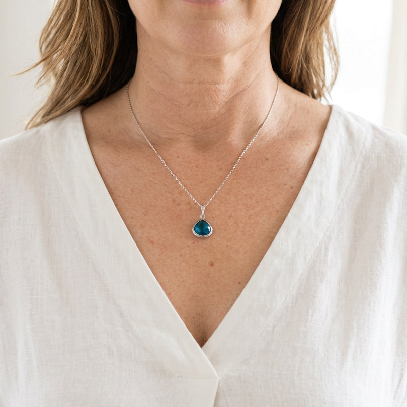 Woman wearing a silver Mini Pebble necklace with a Capri blue faceted glass drop