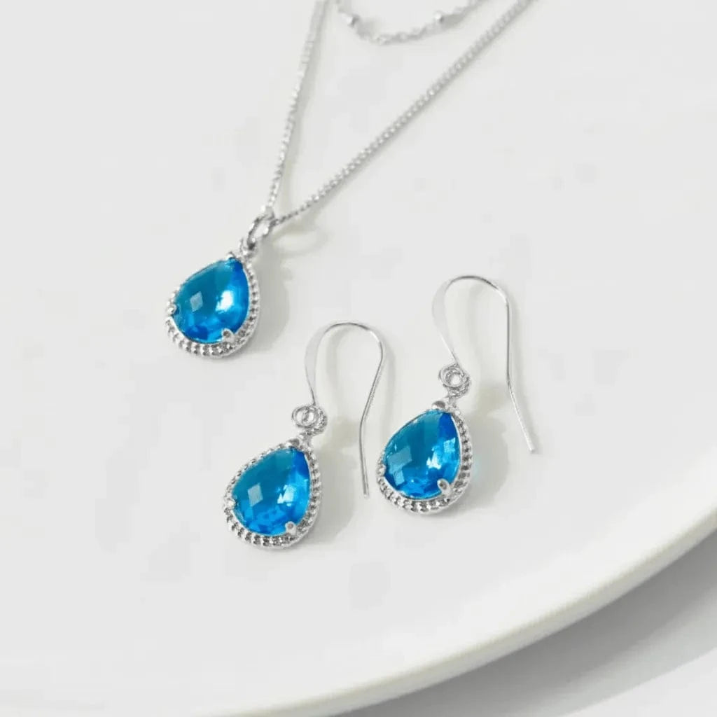 Jewelry set with blue teardrop-shaped gemstones on a white background