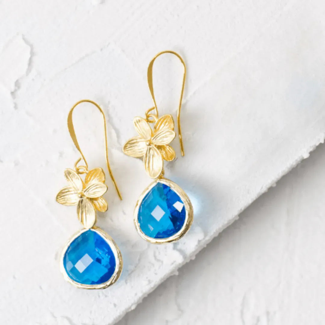 Gold earrings with blue teardrop stones on a white background