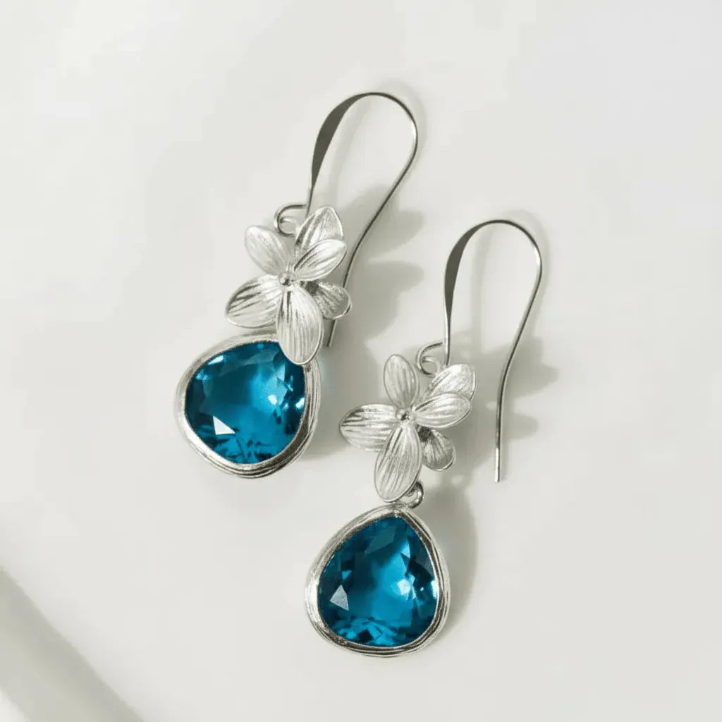 Silver earrings with blue teardrop stones on a white background