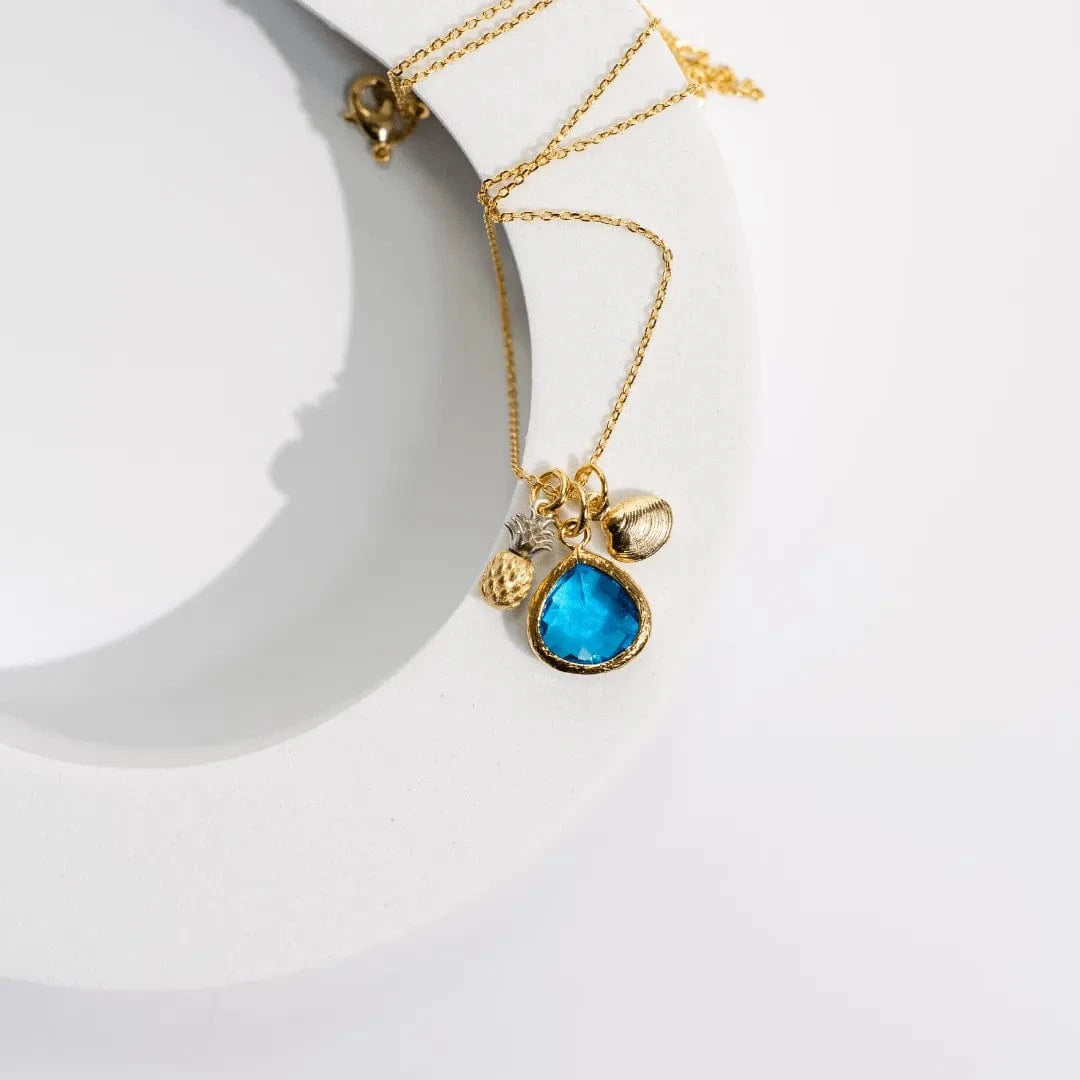 Gold necklace with a blue pendant on a white background