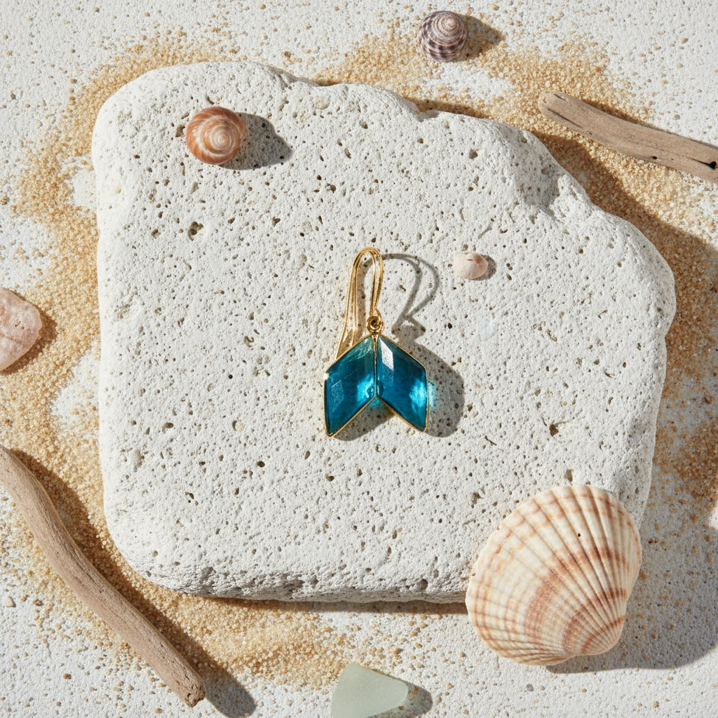 Gold earring with blue gemstones on a light gray background