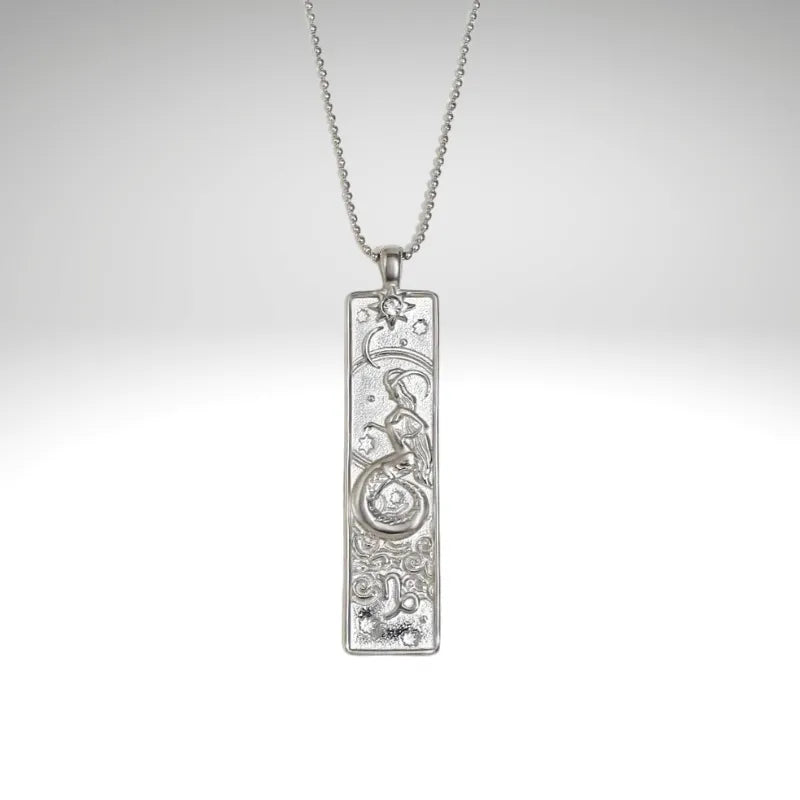 Silver pendant necklace with intricate design on a light gray background