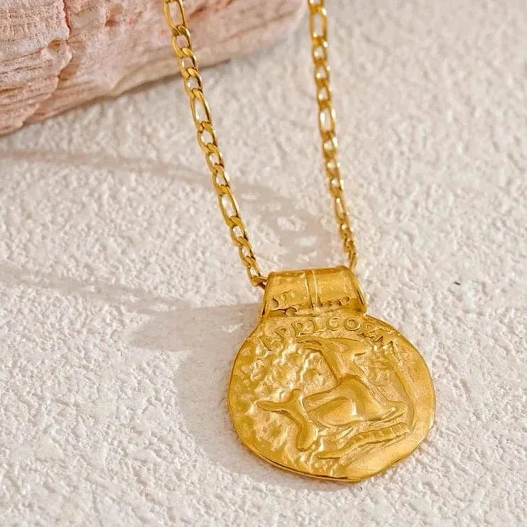 Gold necklace with a coin pendant on a textured surface