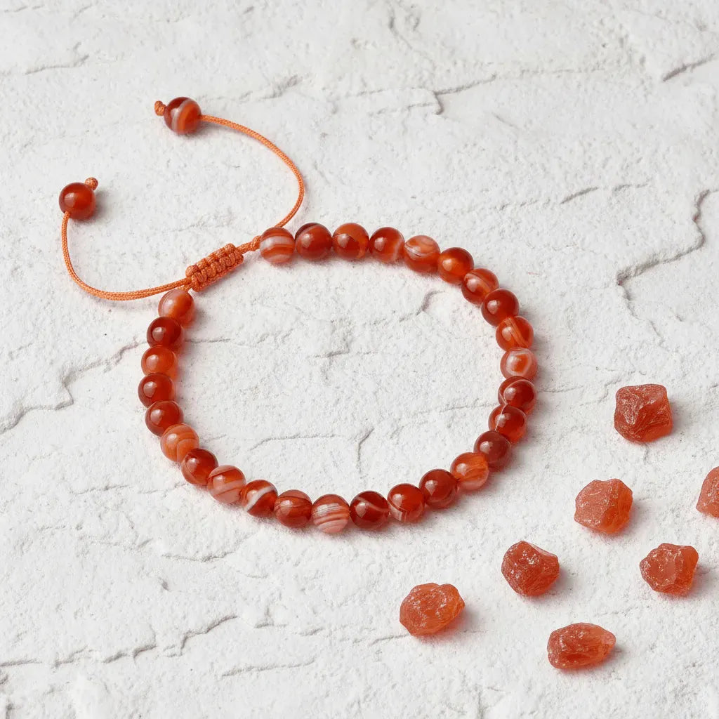 Carnelian beaded bracelet on a textured white surface with loose beads.