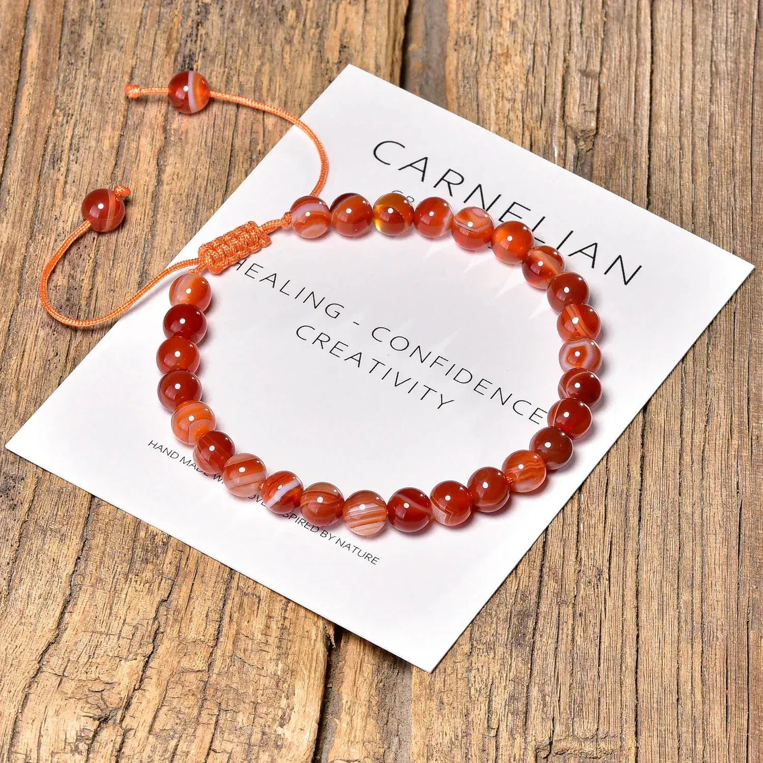 Carnelian bracelet on a wooden surface with a card describing its properties.