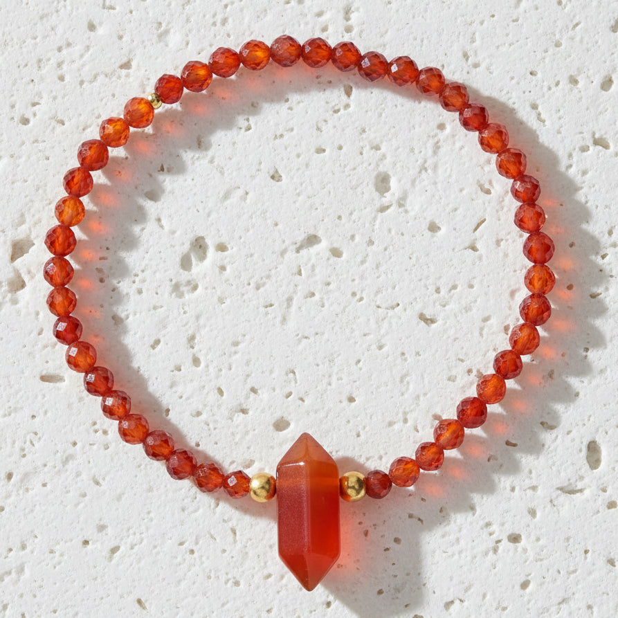Bracelet with red beads and a large red stone on a white background