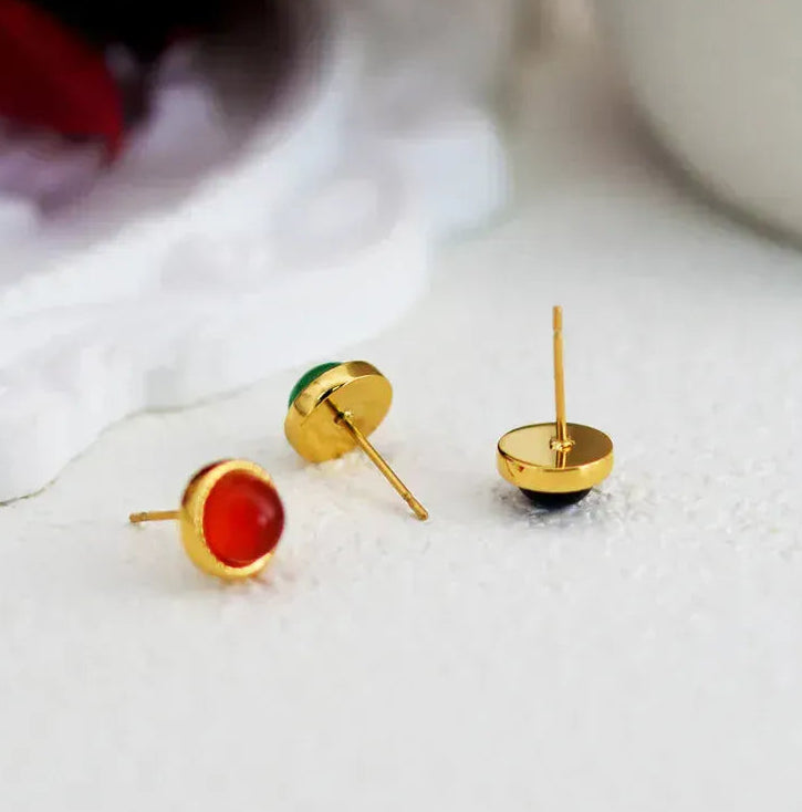 Gold earrings with colorful stones on a white surface