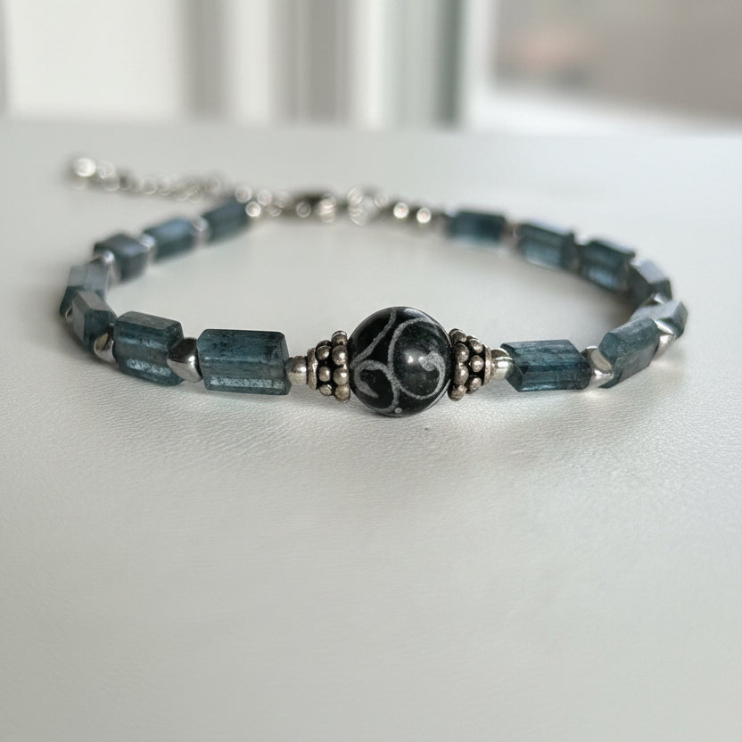 Close-up of a carved agate dzi bead set between faceted teal kyanite beads
