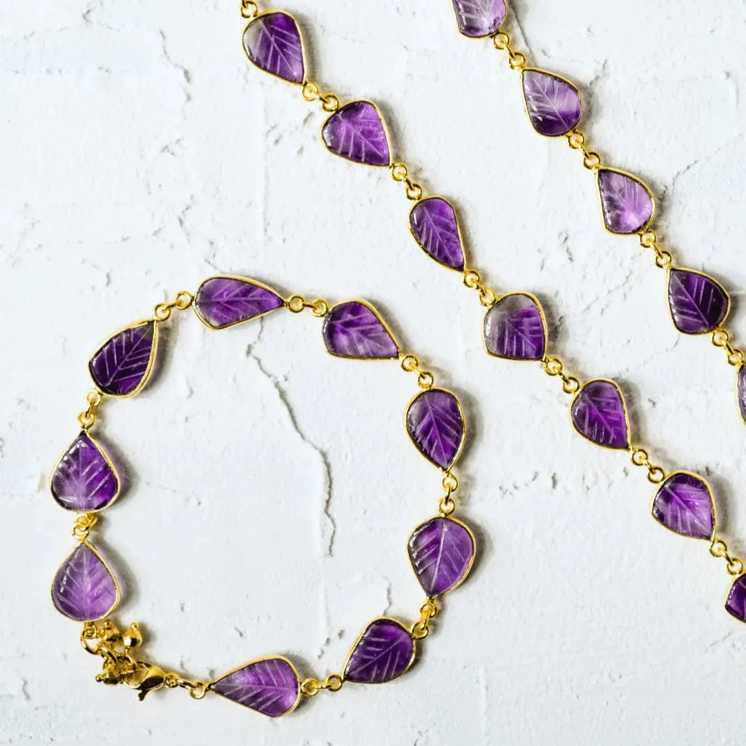Purple leaf-shaped beads on a gold chain against a white background
