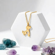 Gold dog-shaped pendant necklace on a white stand with crystals in the background
