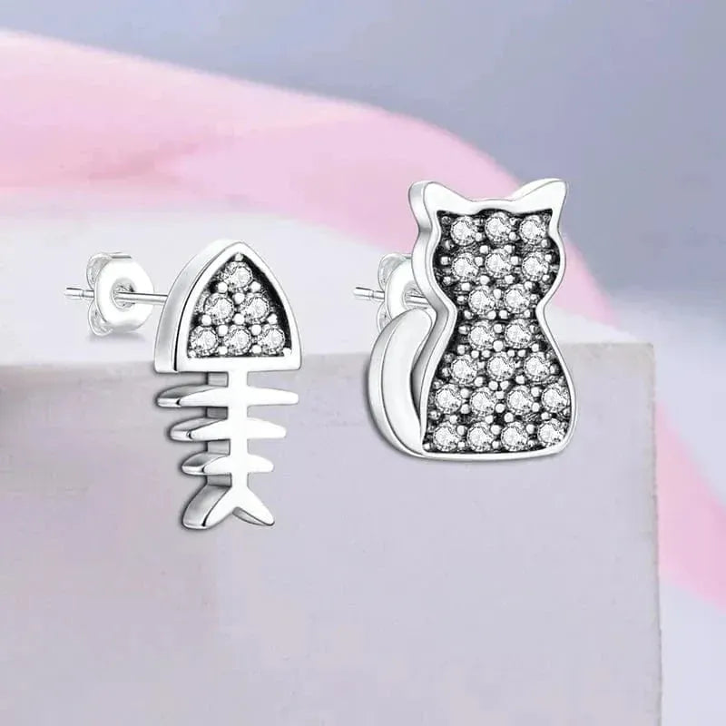Cat-shaped earrings with diamond accents on a pink and gray background