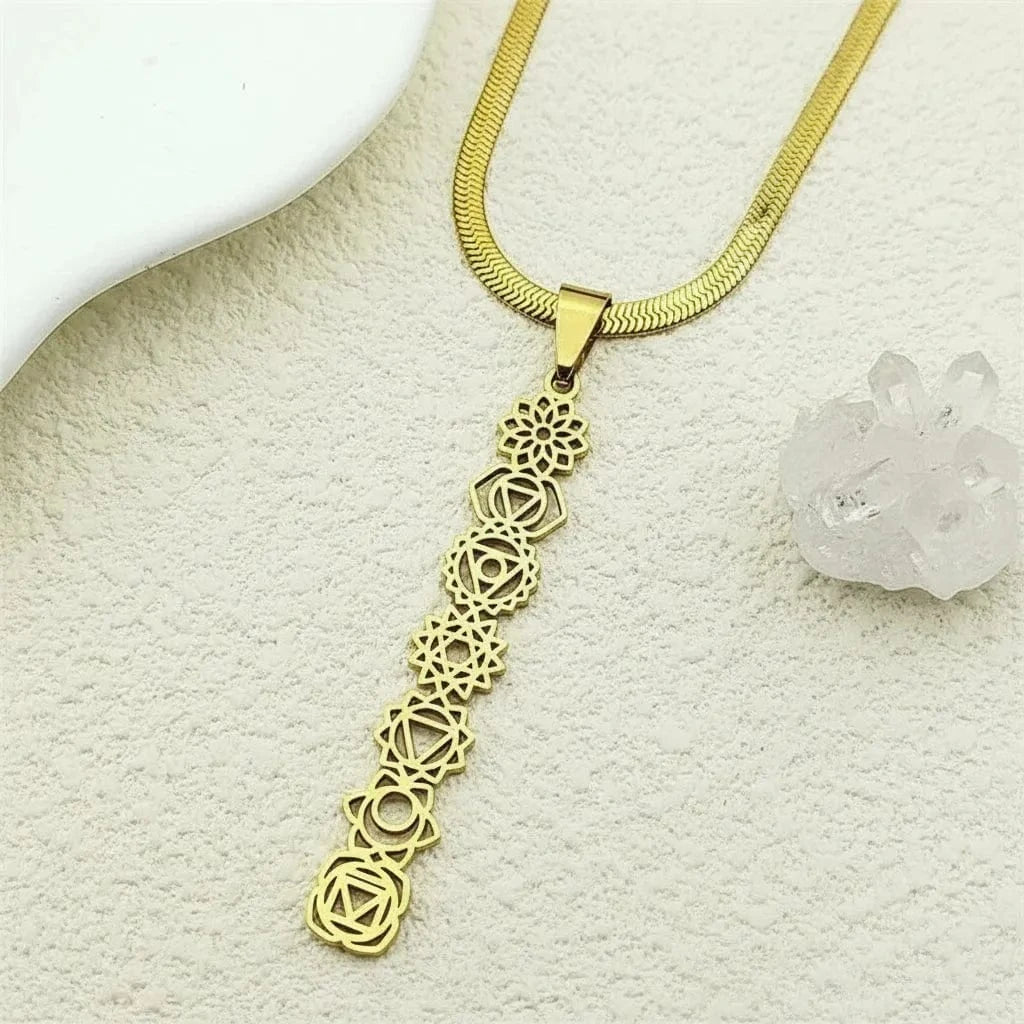 Gold necklace with a detailed pendant on a textured beige surface