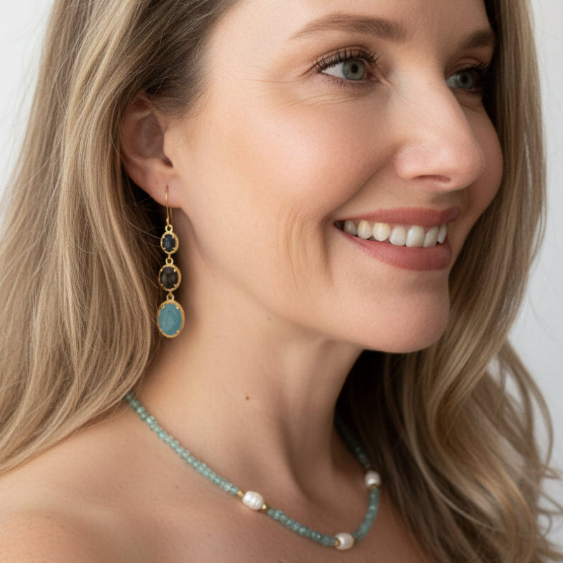 Woman wearing an aquamarine drop earring and beaded necklace — one-of-a-kind crystal necklace for calm