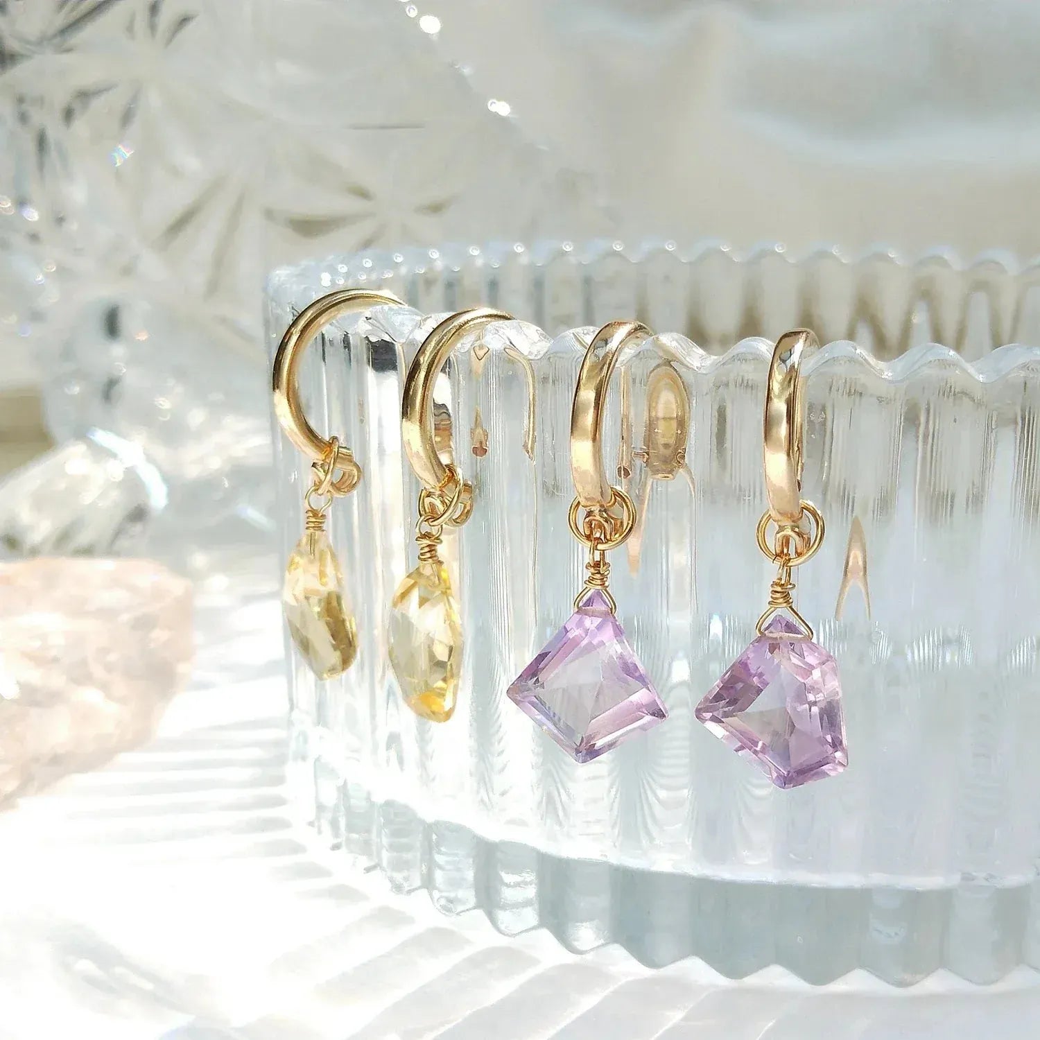 Gold earrings with pink gemstones on a clear stand