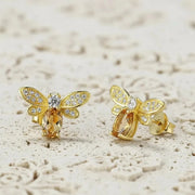 Gold bee-shaped earrings with gemstones on a light background