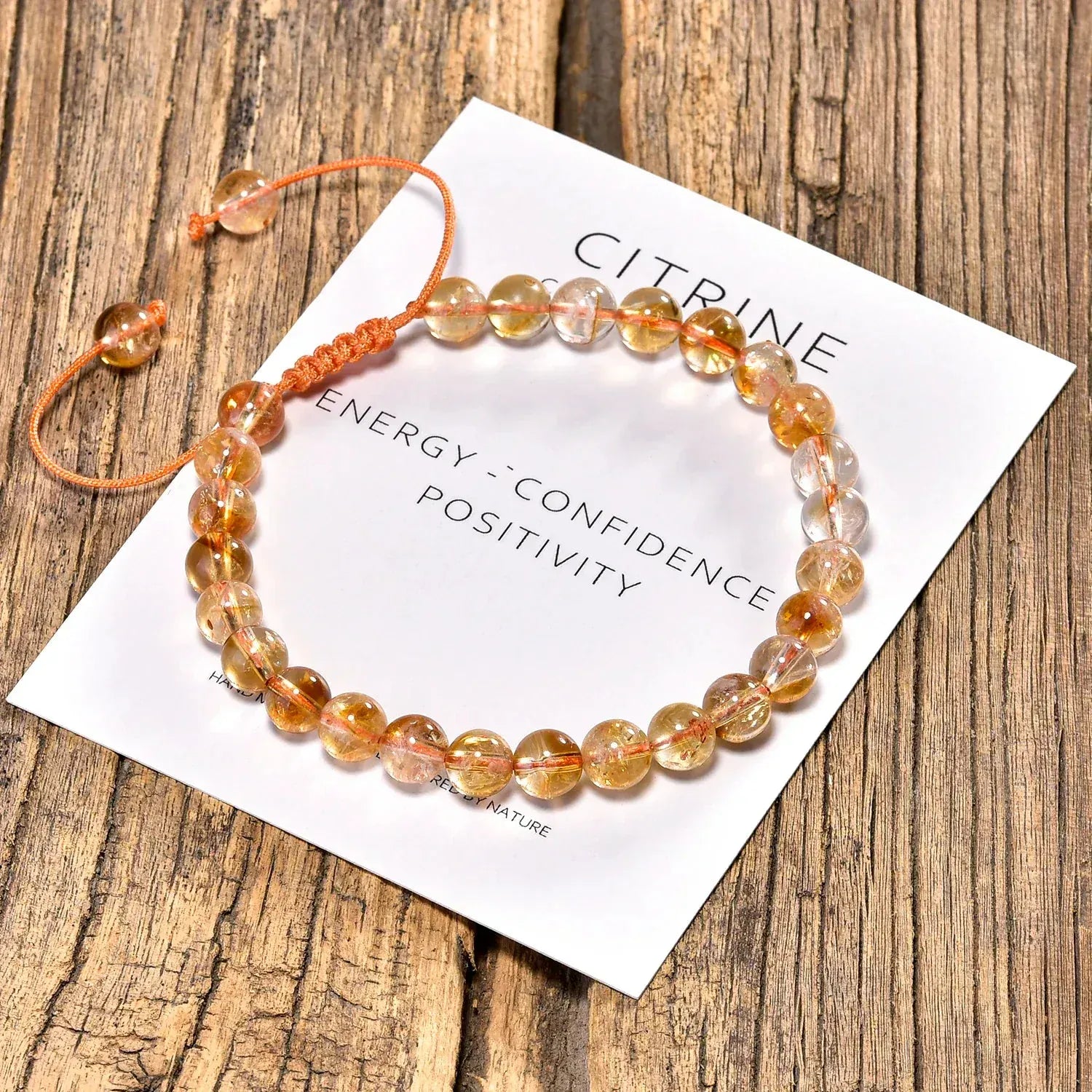 Citrine bracelet on a card with energy, confidence, positivity text on a wooden surface