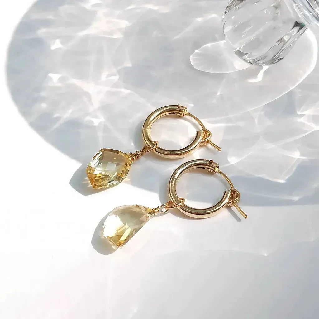 Gold hoop earrings with citrine stones on a white background