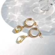Gold hoop earrings with citrine stones on a white background