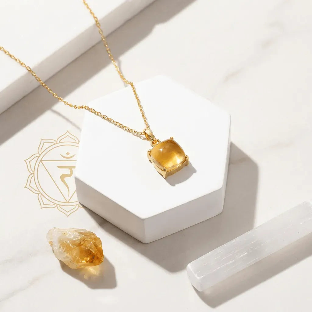 Gold necklace with a citrine pendant on a white surface