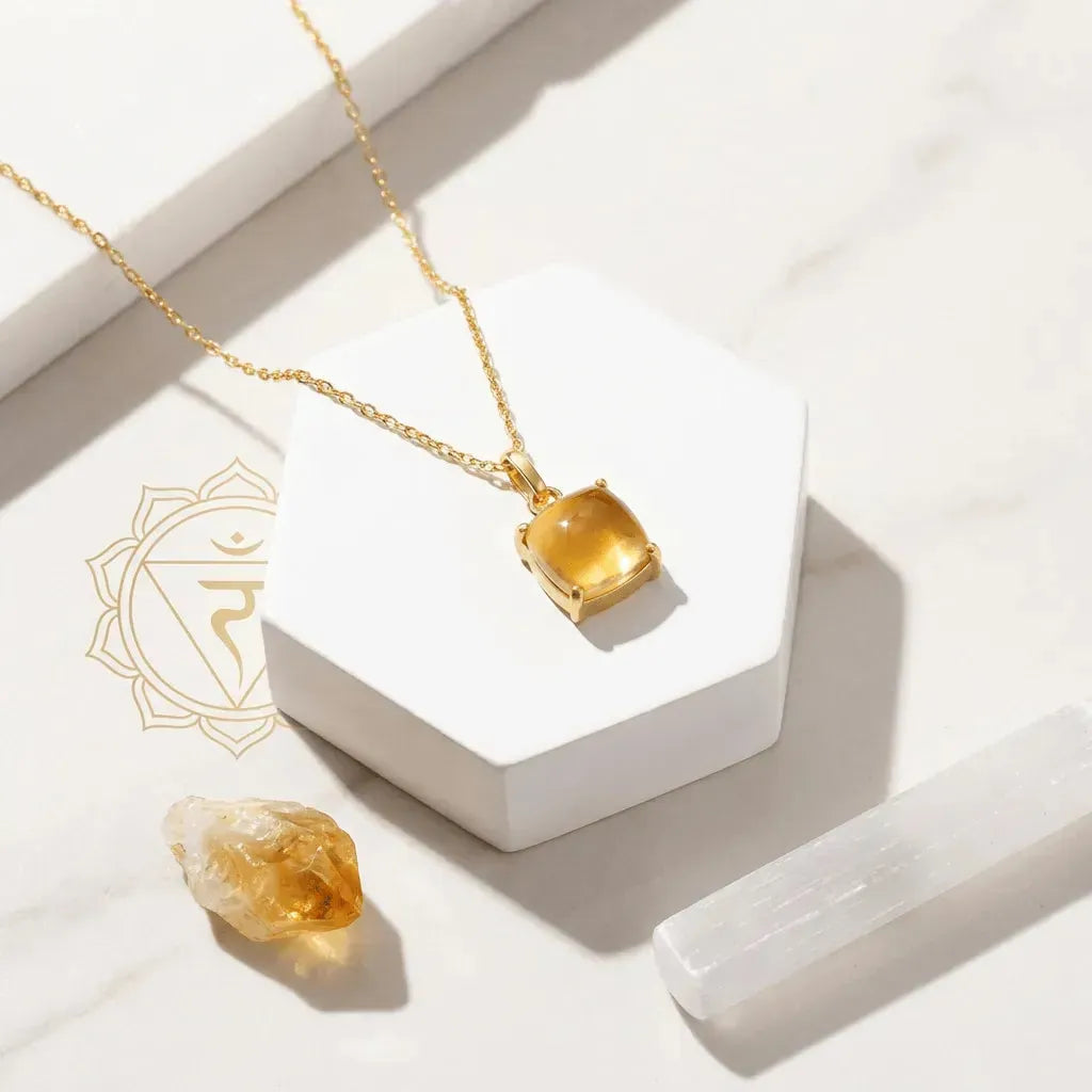 Gold necklace with a citrine pendant on a white surface