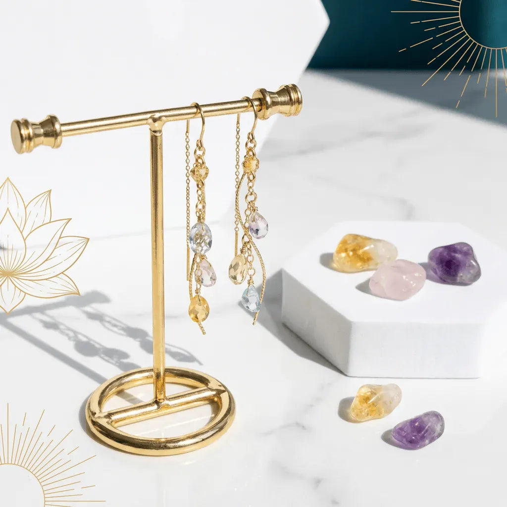 Gold earring stand with hanging earrings on a white surface with crystals.